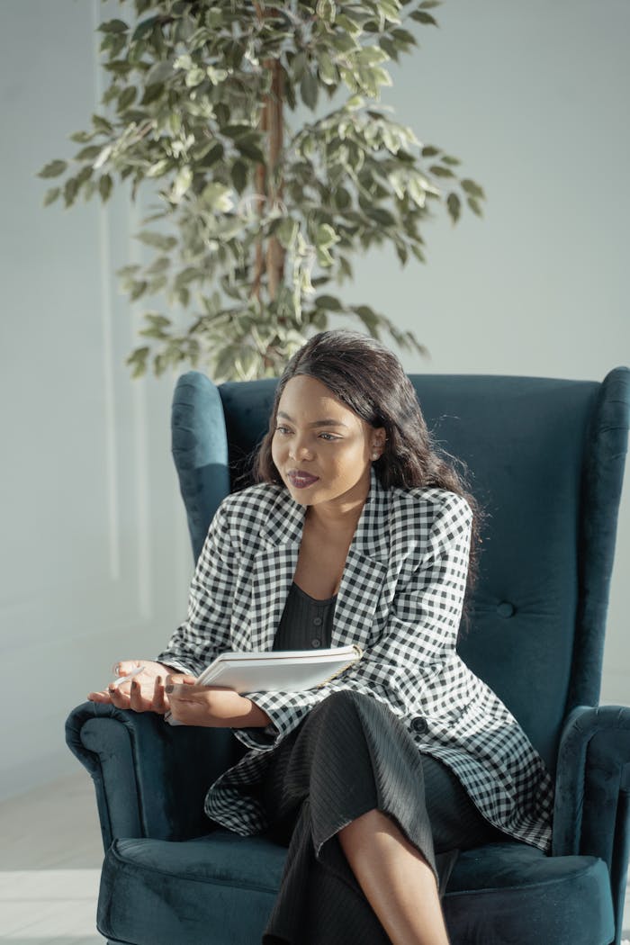 services-02 Businesswoman in a checkered jacket taking notes indoors, focused and engaged.